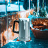 Beer Stein Stainless steel beer stein filled with frothy beer beside a basket of ribs and chips, featuring an insulated beer mug design perfect for serving cold drinks with meals.